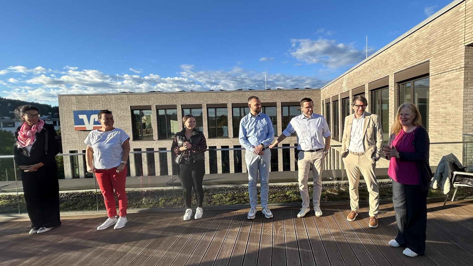 Achtsamkeit am Morgen Kollegen der Volksbank Bodensee-Oberschwaben auf der Dachterrasse bei Achtsamkeitsübungen vor blauem Himmel.